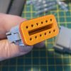 Deutsch DT06-12S-C015 12-way socket plug face view showing orange wedge-lock TPA fully seated with twelve socket cavities visible — Voltforge 430019-000