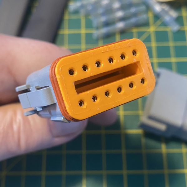 Deutsch DT06-12S-C015 12-way socket plug face view showing orange wedge-lock TPA fully seated with twelve socket cavities visible — Voltforge 430019-000