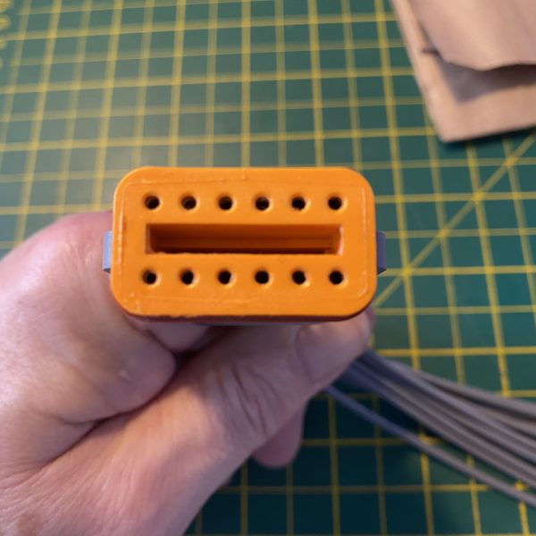 Deutsch DT06-12S-C015 12-way socket plug face view showing orange wedge-lock TPA fully seated with twelve socket cavities and keying slot visible — Voltforge 430019-000